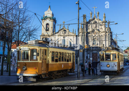 Vintage trams in Vitoria parish of Porto, Portugal. Carmelite Church (Igreja dos Carmelitas Descalcos), Carmo Church (Igreja do Carmo) on background Stock Photo