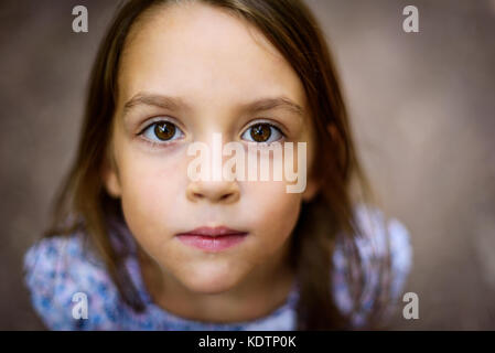 Portrait of little girl looking up at the parent outdoors. A child is looking up towards the camera outside in the woods. Shallow depth of field and s Stock Photo