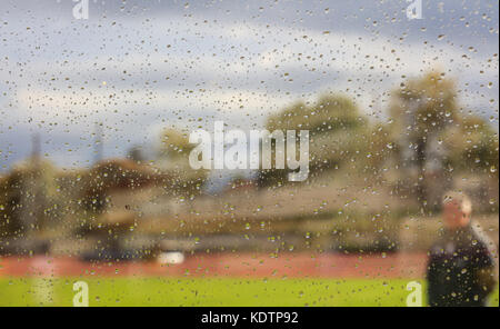 A coach on green grass during a rainy day, view through a glass with tiny raindrops. Abstract and blurred. Stock Photo