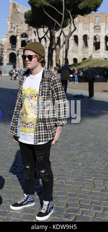 Young man in Rome walking across the road in the vicinity of the Colosseum. Stock Photo