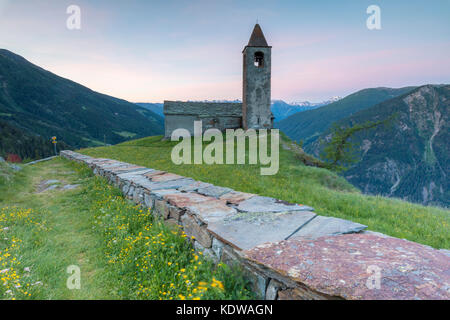 Ancient church at sunrise, San Romerio Alp, Brusio, Canton of Graubünden, Poschiavo valley, Switzerland Stock Photo