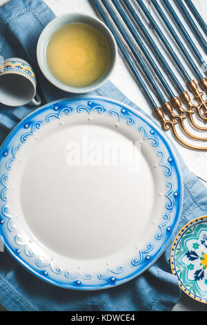 Large plate and olive oil in a bowl, Hanukkah on a table vertical Stock Photo