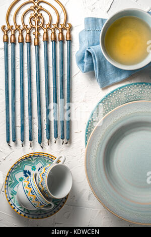 Hanukkah with candles, plates, butter in a bowl and blue napkin top view vertical Stock Photo