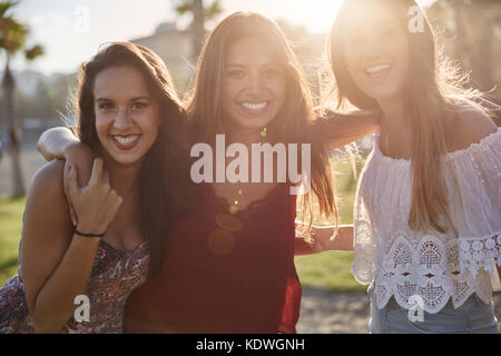 Portrait of three happy girls standing together in sunlight smiling Stock Photo