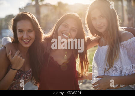 Portrait of three beautiful girls standing together in sunlight smiling Stock Photo