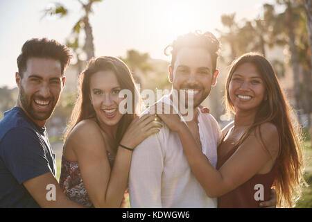 Portrait of four happy friends standing together outside in smiling Stock Photo