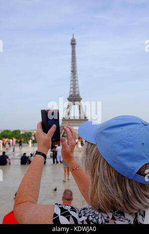 A female tourist takes a photo of the Eiffel Tower in Paris on a summers day Stock Photo