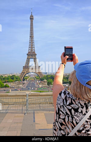 A female tourist takes a photo of the Eiffel Tower in Paris on a summers day Stock Photo