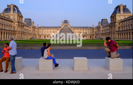 Tourists relaxing in front of the Louvre in Paris, with a tourist posing as The Thinkert Stock Photo