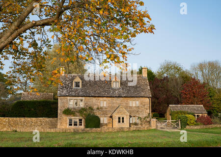 Cotswold stone cottage and autumn trees in Wyck Rissington, Cotswolds, Gloucestershire, England Stock Photo