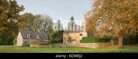 Cotswold stone cottages and autumn trees in Wyck Rissington, Cotswolds, Gloucestershire, England. Panoramic Stock Photo