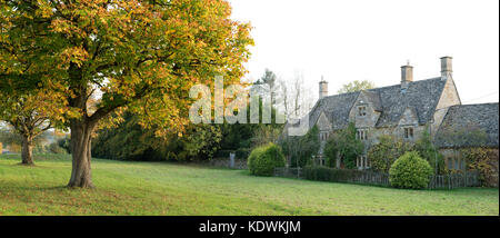 Cotswold stone cottage and autumn trees in Wyck Rissington, Cotswolds, Gloucestershire, England. Panoramic Stock Photo