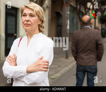 angry retiree blond woman being irritated with man standing back to her in town Stock Photo