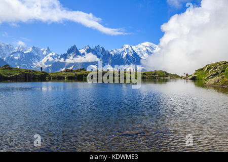 Low clouds and mist around Grandes Jorasses and Mount Blanc while hikers proceed on Lac De Cheserys Haute Savoie France Europe