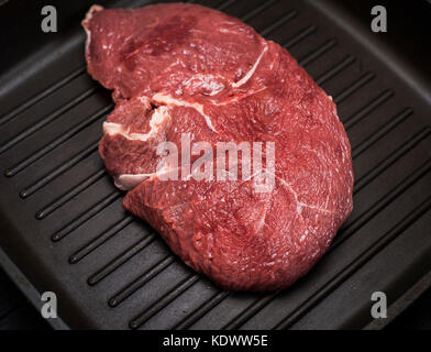 raw beef steak on a black frying pan, close up Stock Photo