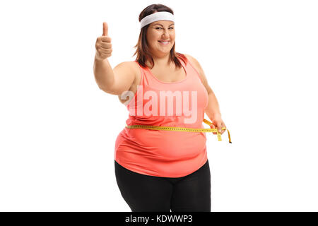 Overweight woman measuring her waist with a measuring tape and making a thumb up sign isolated on white background Stock Photo