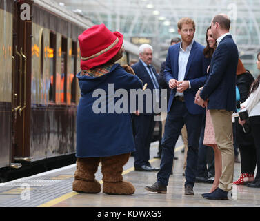 The Duke and Duchess of Cambridge and Prince Harry with a costumed figure of Paddington bear on platform 1 at Paddington Station, London, as they attend the Charities Forum event, joining children from the charities they support and meeting the cast and crew from the forthcoming film Paddington 2. Stock Photo