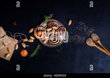 Christmas decorations and food, dried orange slices and nuts. New year holiday theme background. Above view, space for text. Stock Photo