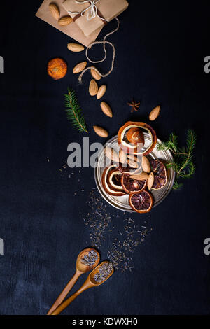 New year holiday theme background. Christmas decorations and food, dried orange slices and nuts. Above view, space for text. Stock Photo