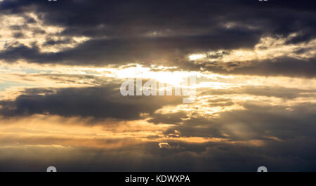 Amazing pattern from the clouds in the sky during the sunset. Beautiful, golden sunbeams cover the sky. Stock Photo