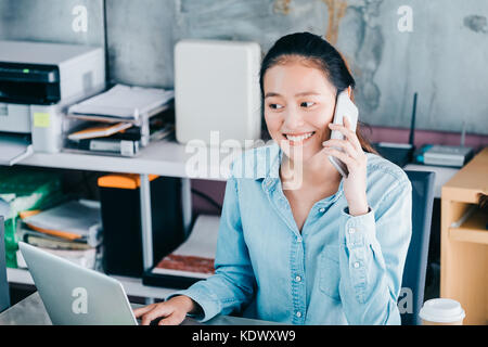 Asian creative designer contact customer at mobile pone with smiling face,start up owner company concept. Stock Photo