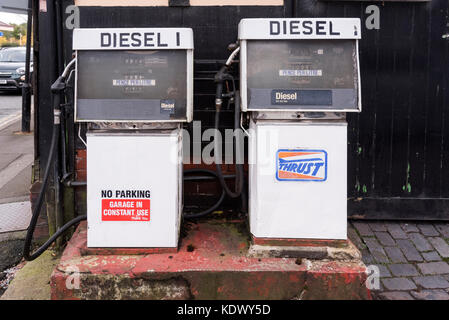 Two old fashion diesel pumps on a garage forecourt.