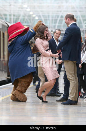 The Duke of Cambridge watches as his wife the Duchess of Cambridge dances with a costumed figure of Paddington bear on platform 1 at Paddington Station, London, as they attend the Charities Forum event, joining children from the charities they support and meeting the cast and crew from the forthcoming film Paddington 2. Stock Photo