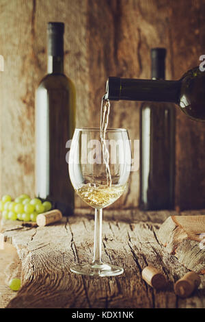 Wine. Glass of white wine in wine cellar. Old white wine on wood. Stock Photo