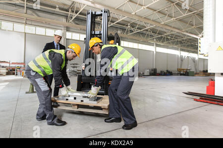 Workers taking aluminium billet at CNC machine shop Stock Photo