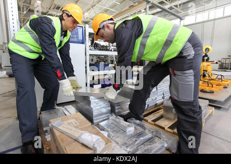 Workers taking aluminium billet at CNC machine shop Stock Photo