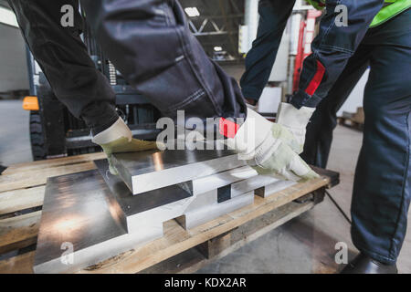 Workers taking aluminium billet at CNC machine shop Stock Photo