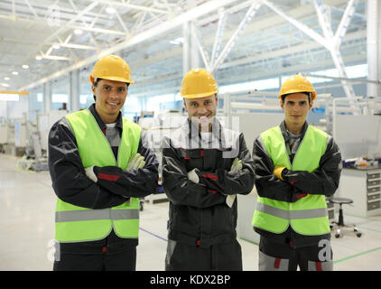 Team of three positive smiling workers in CNC factory Stock Photo