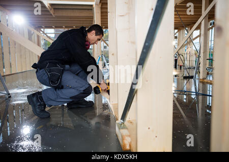 Full length side view of carpenter drilling wood at construction site Stock Photo