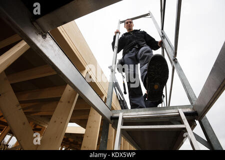 Low angle view of male carpenter moving down ladder of incomplete building Stock Photo