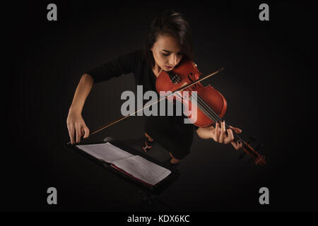 Beautiful Violinist Woman playing violin on black background Stock Photo