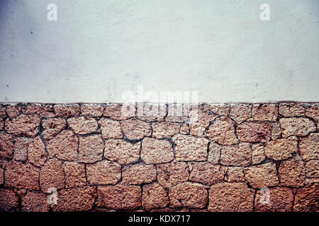 Old dirty partly clay brick wall, background or wallpaper with copy space, color toning applied. Stock Photo
