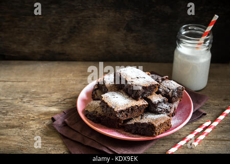 Brownies for Christmas and winter holidays. Homemade chocolate fudge brownies with milk on rustic wooden table. Stock Photo