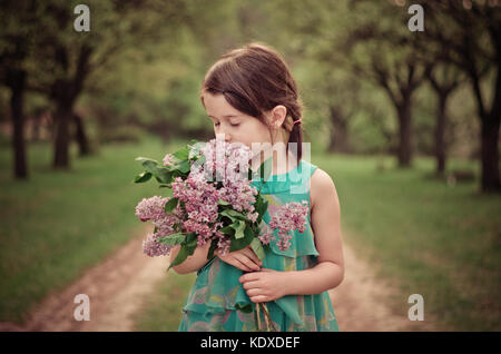 Pretty girl holding bouquet of flowers and smelling. Eyes closed, romantic image. Stock Photo