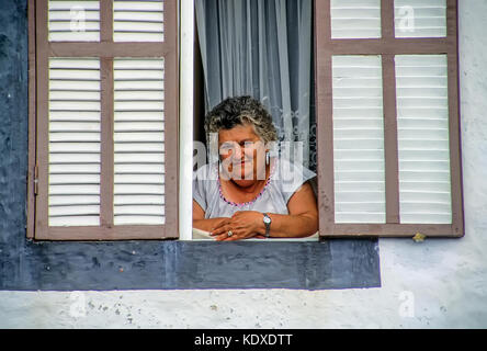 Portrait of a matronly Azorian Portuguese woman gazing serenely as she leans out her home window on Pico Island, Azores Stock Photo