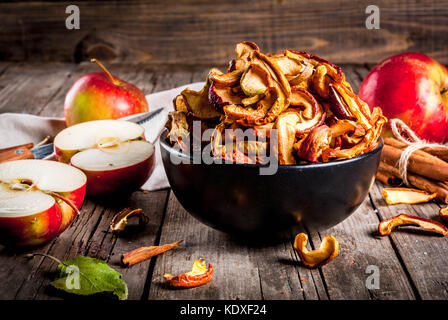 Homemade sun-dried organic apple slices, crispy apple chips, on an old rustic wooden table with fresh apple and cinnamon. Copy space Stock Photo