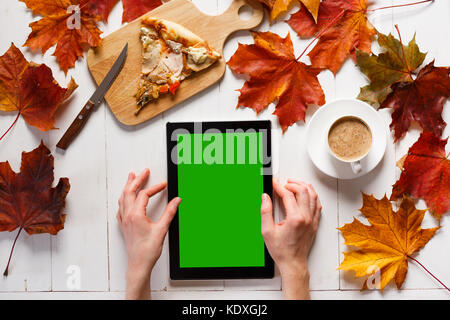 Womans hands with tablet with blank screen. Female using tablet and drinking coffee with pizza. Stock Photo