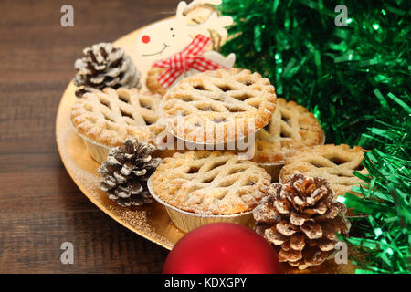 Christmas mince pies on a gold plate with white reindeer on a wood background Stock Photo