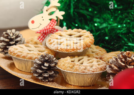 Christmas mince pies on a gold plate with white reindeer on a wood background Stock Photo