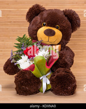Teddy bear holding bouquet of red roses valentines day Stock Photo - Alamy