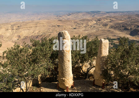 Roman milestone pillars in foreground, which lined the ancient pilgrimage route between Jerusalem and Mount Nebo, Jordan, overlooking a desert valley Stock Photo