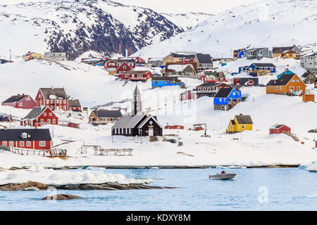 Arctic settlement with colorful Inuit houses on the rocky hills covered in snow with snow and mountain in the background, Ilulissat, Greenland Stock Photo