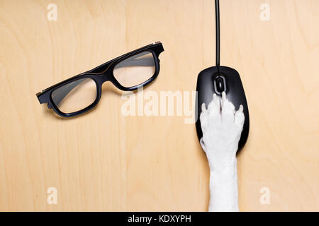 dog paw clicking on a pc computer mouse, searching , and looking online in internet finding information , isolated on wood desk Stock Photo