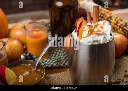 Warm apple pumpkin cider with fall decorations and caramel dip with candles. Stock Photo