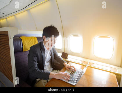 Asian businessman working on laptop in the luxury airplane Stock Photo