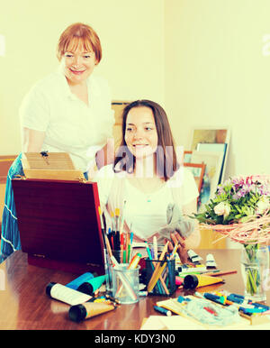 Smiling experienced mature teacher gives advice to the beginner. Focus on the young woman Stock Photo
